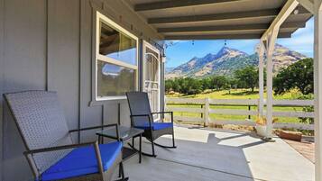 Eine überdachte Veranda mit Korbstühlen und Blick auf die Berge.