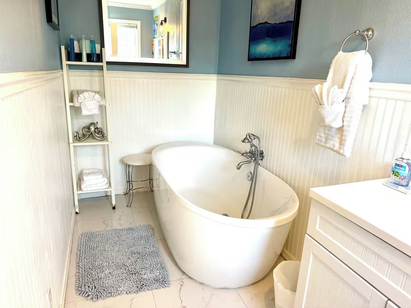 Ein Badezimmer mit einer freistehenden Badewanne, einem Waschtisch mit Handtuchhalter und einem Ablagebereich für Toilettenartikel.