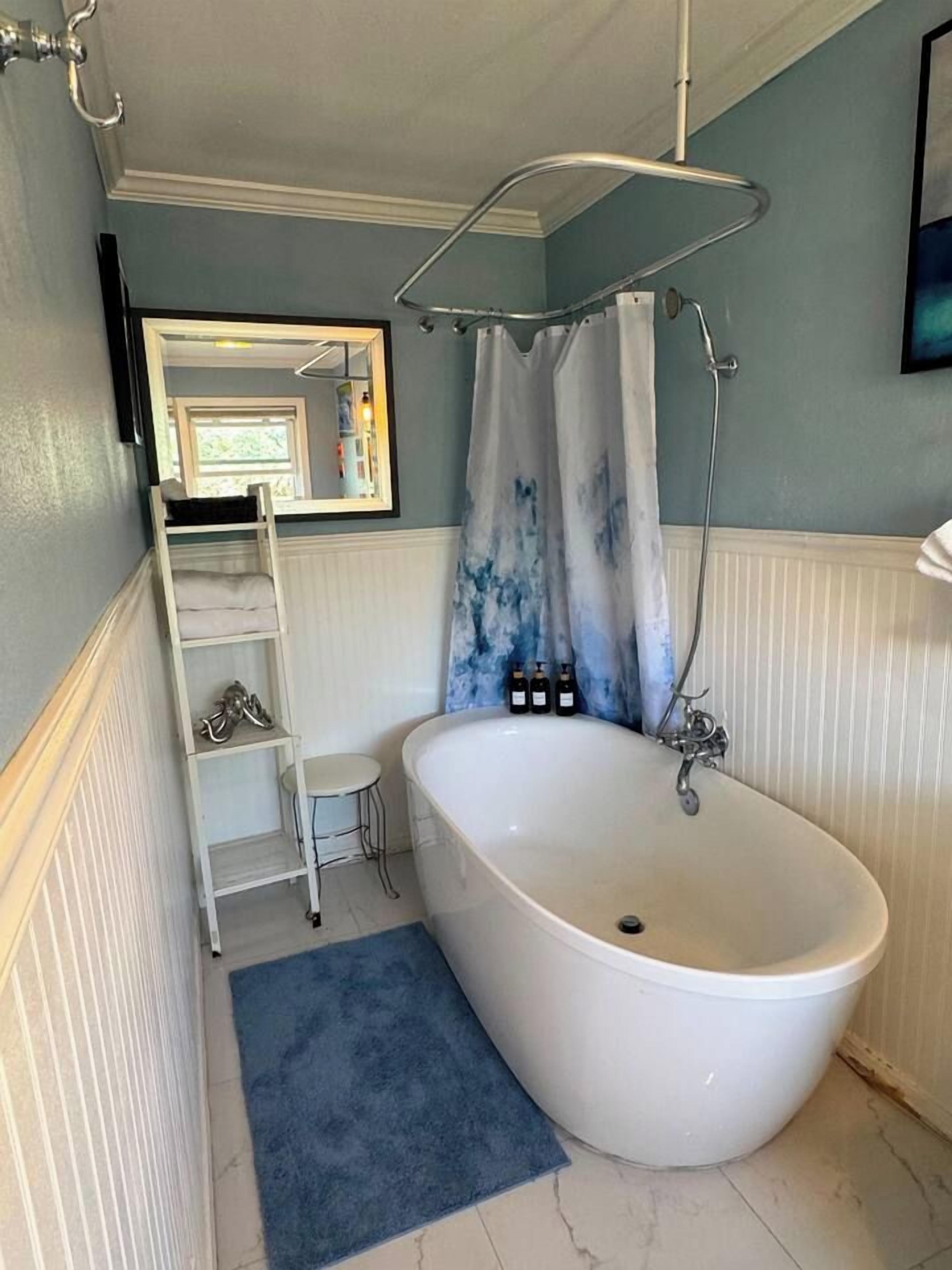 Ein Badezimmer mit einer freistehenden Badewanne, einer Dusche, einem weißen Waschtisch und einer Sprosse.