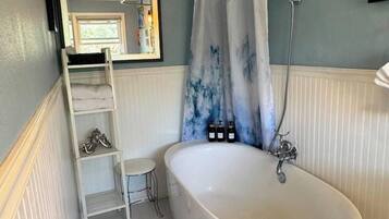 Ein Badezimmer mit einer freistehenden Badewanne, einer Dusche, einem weißen Waschtisch und einer Sprosse.