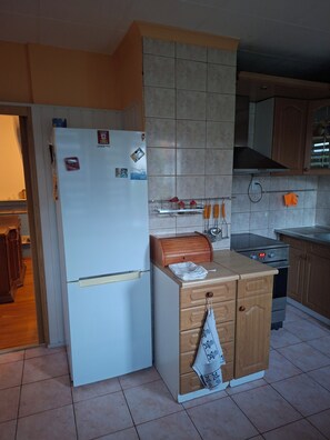 A compact kitchen with a white refrigerator, wooden cabinets, and a built-in oven. - Spacious Home with fireplace, garden and ponds. (Kołobrzeg)