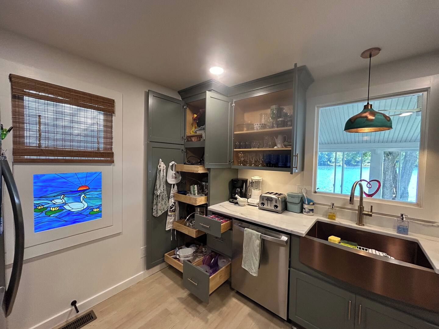A compact kitchen with a built-in dishwasher, a stainless steel sink, and a window with a view of the outdoors.