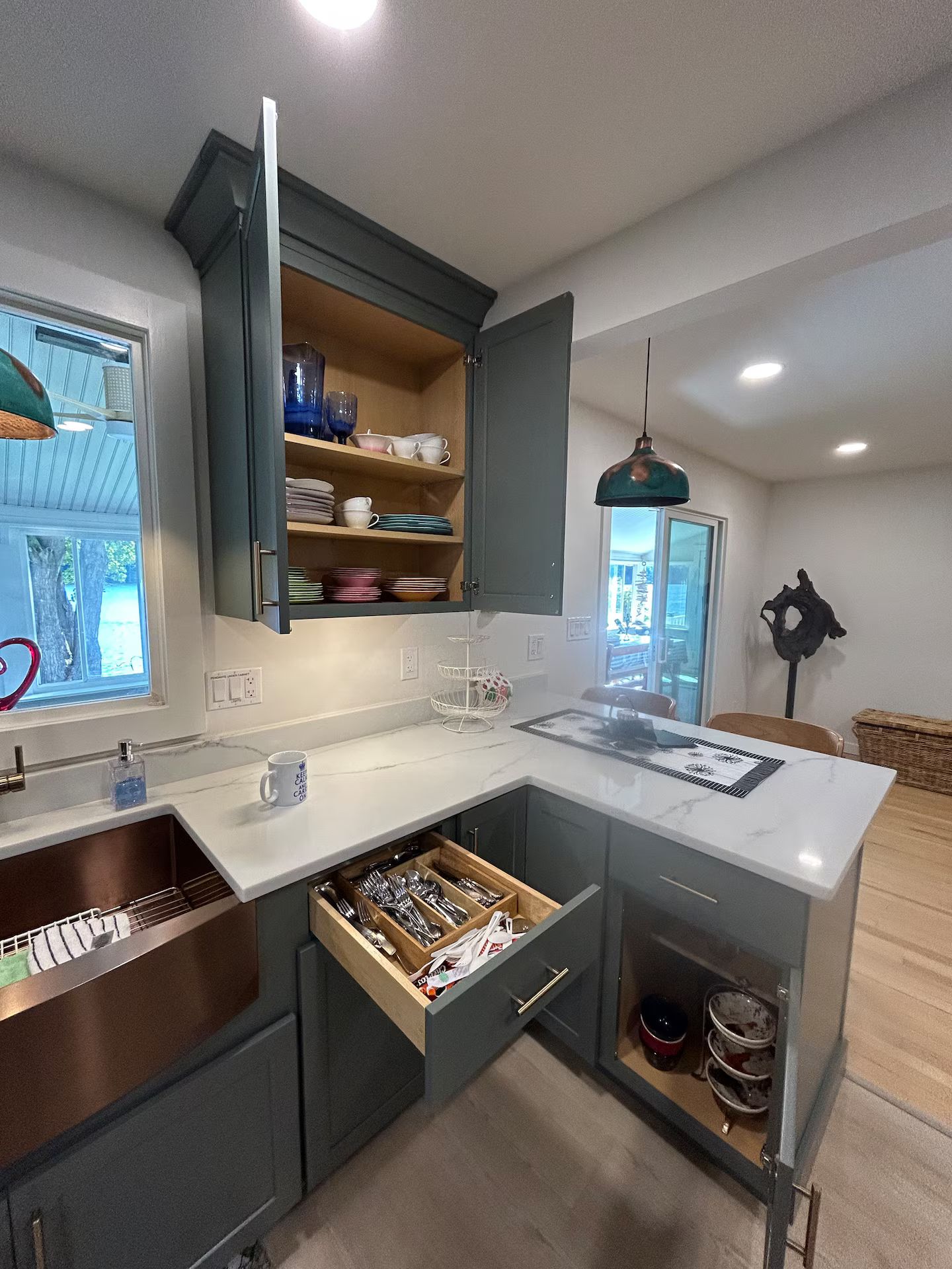 A modern kitchen with a built-in island, open shelving, and a pendant light.