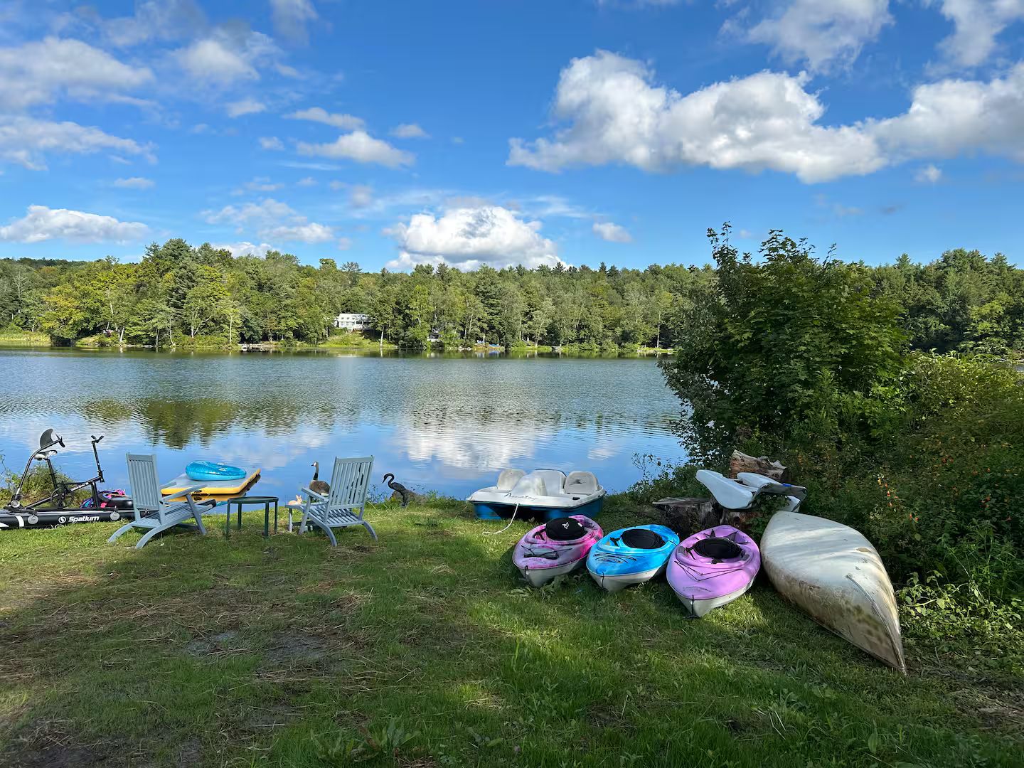 Eine Seenlandschaft mit Kajaks, einem Stand-Up-Paddleboard und einem Fahrrad.