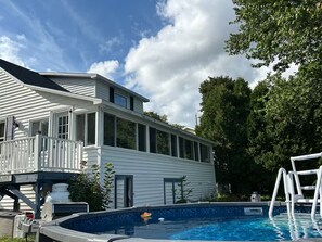 Ein Haus mit Swimmingpool, überdachter Terrasse und umzäunter Fläche.
