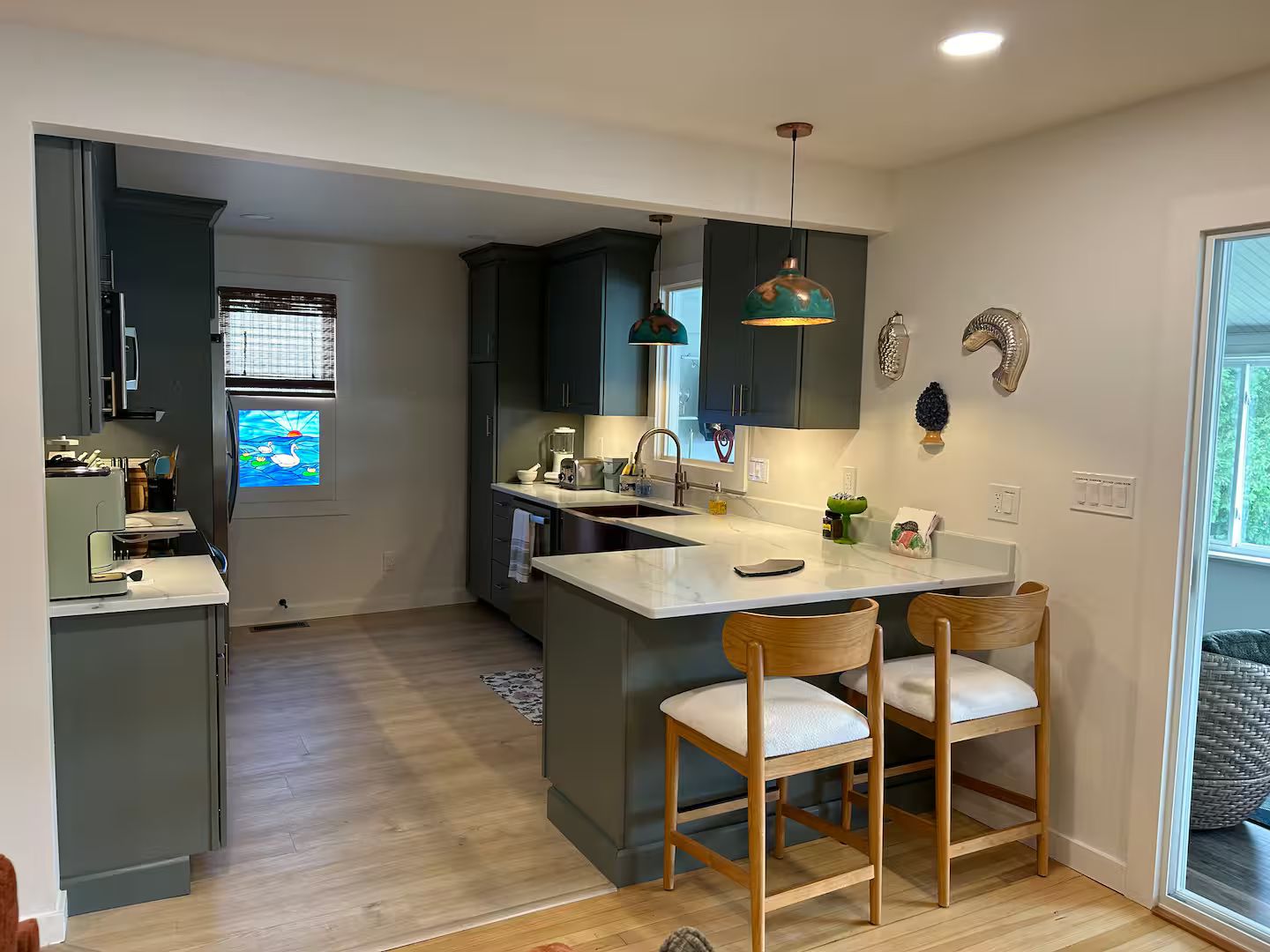 A modern kitchen with dark cabinets, a central island, bar stools, and pendant lighting.