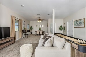 A living room with a television, sofa, and a dining area with a table and chairs. - Immaculate 3BR close to Lake with Game Room | Comfortably sleeps 8! (Lago Vista)