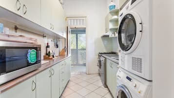 A compact kitchen with a microwave, oven, and stacked washer-dryer unit.