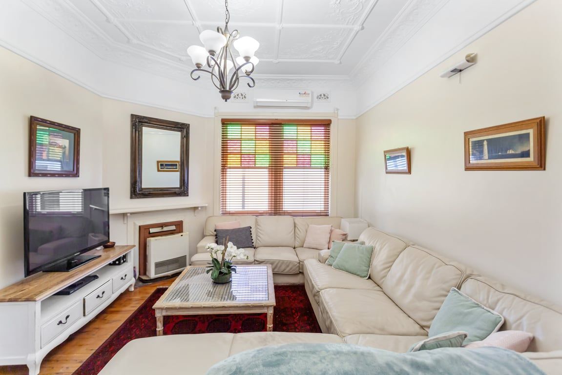 A living room with a television, sofa, coffee table, and decorative items.