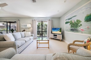 A living room with a sofa, a coffee table, a TV, and a painting on the wall.