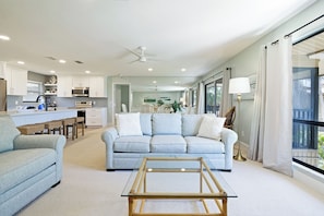 A modern living room with a sofa, a coffee table, and a kitchen area in the background.