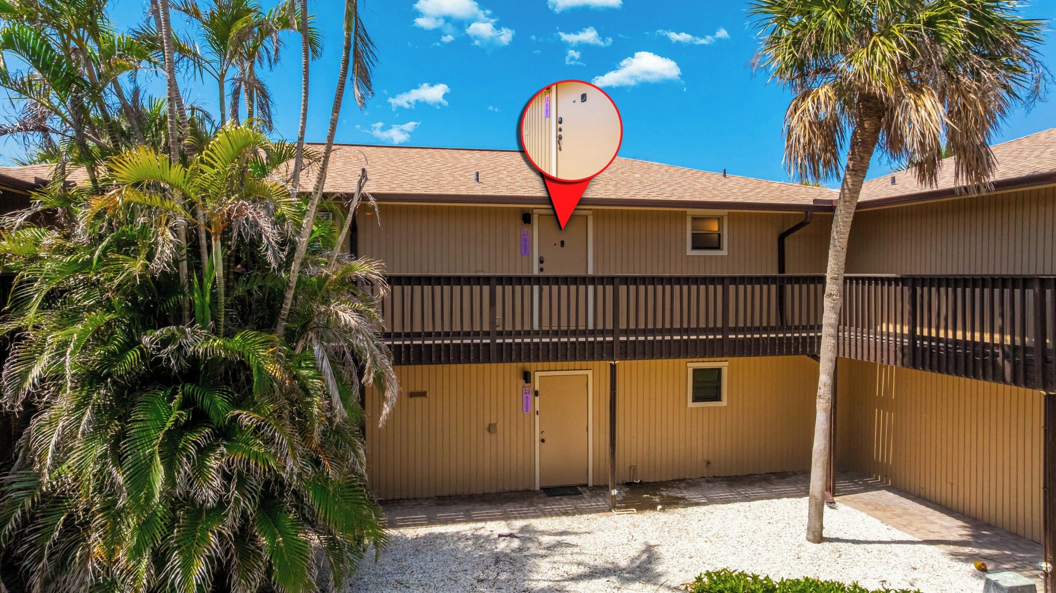 A two-story motel with a fenced courtyard, palm trees, and a red location marker.