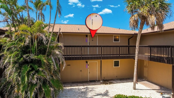 A two-story motel with a fenced courtyard, palm trees, and a red location marker.