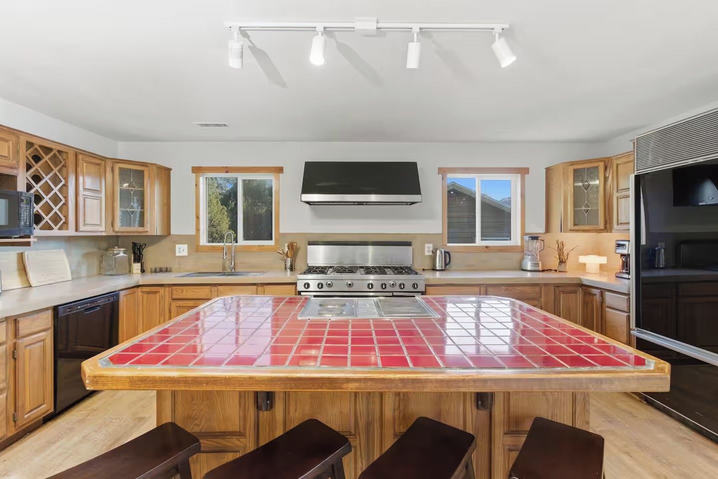 Una cocina moderna con una isla central, armarios de madera y una campana extractora de acero inoxidable.