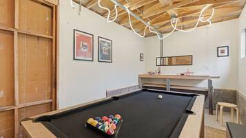A pool table with a set of balls, wooden walls, and framed artwork.