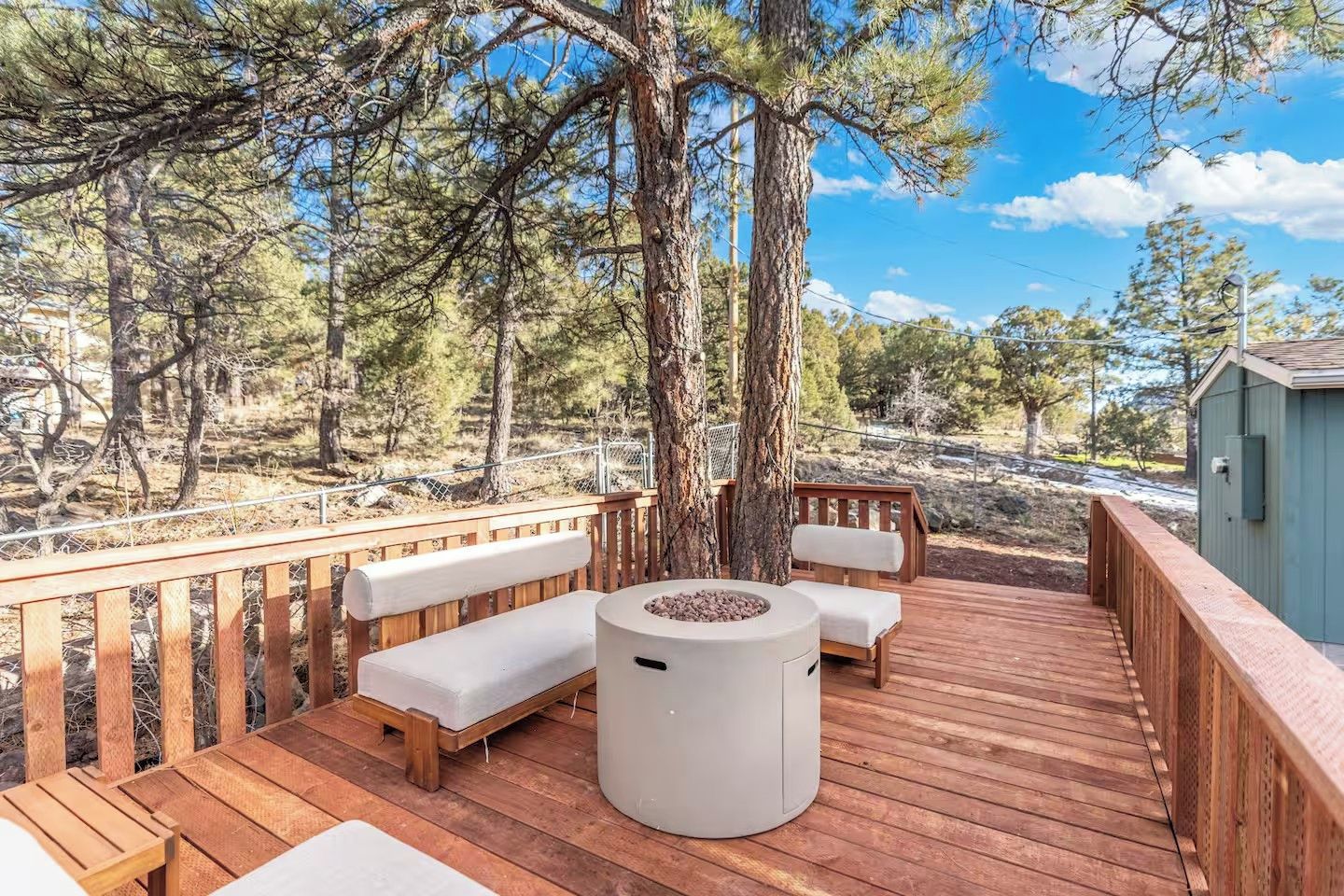 A wooden deck with a built-in bench and a fire pit.