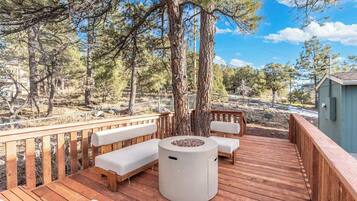 A wooden deck with a built-in bench and a fire pit.