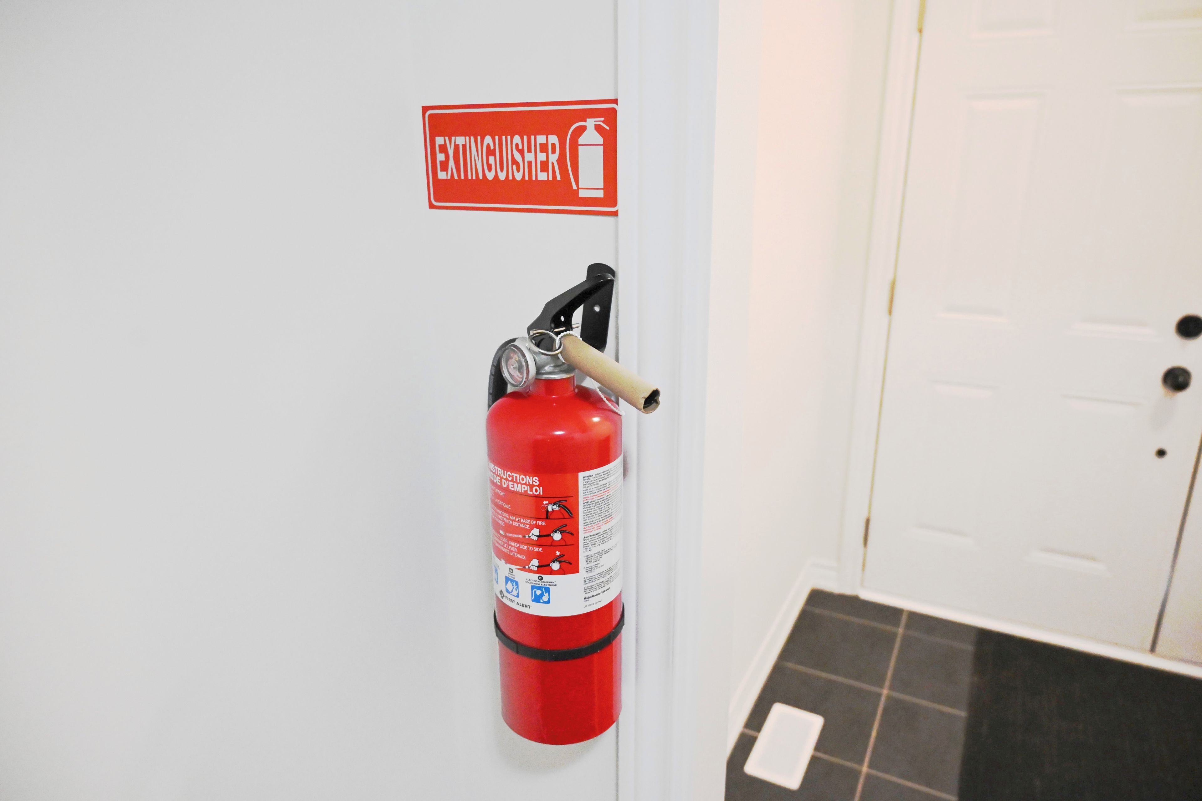 Un extincteur fixé au mur, avec un panneau placé au-dessus.