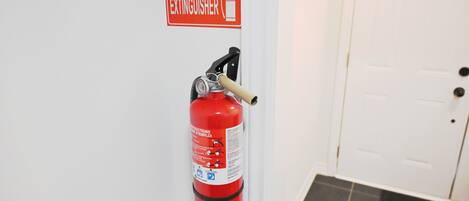 Un extincteur fixé au mur, avec un panneau placé au-dessus.