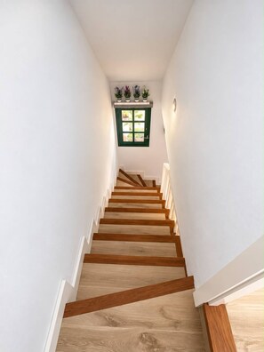 A staircase with wooden steps and white walls, leading to a door with a green frame and a window above it. - Maspalomas Bungalow: Private Terrace, Pool, BBQ, and A/C (San Bartolomé de Tirajana)