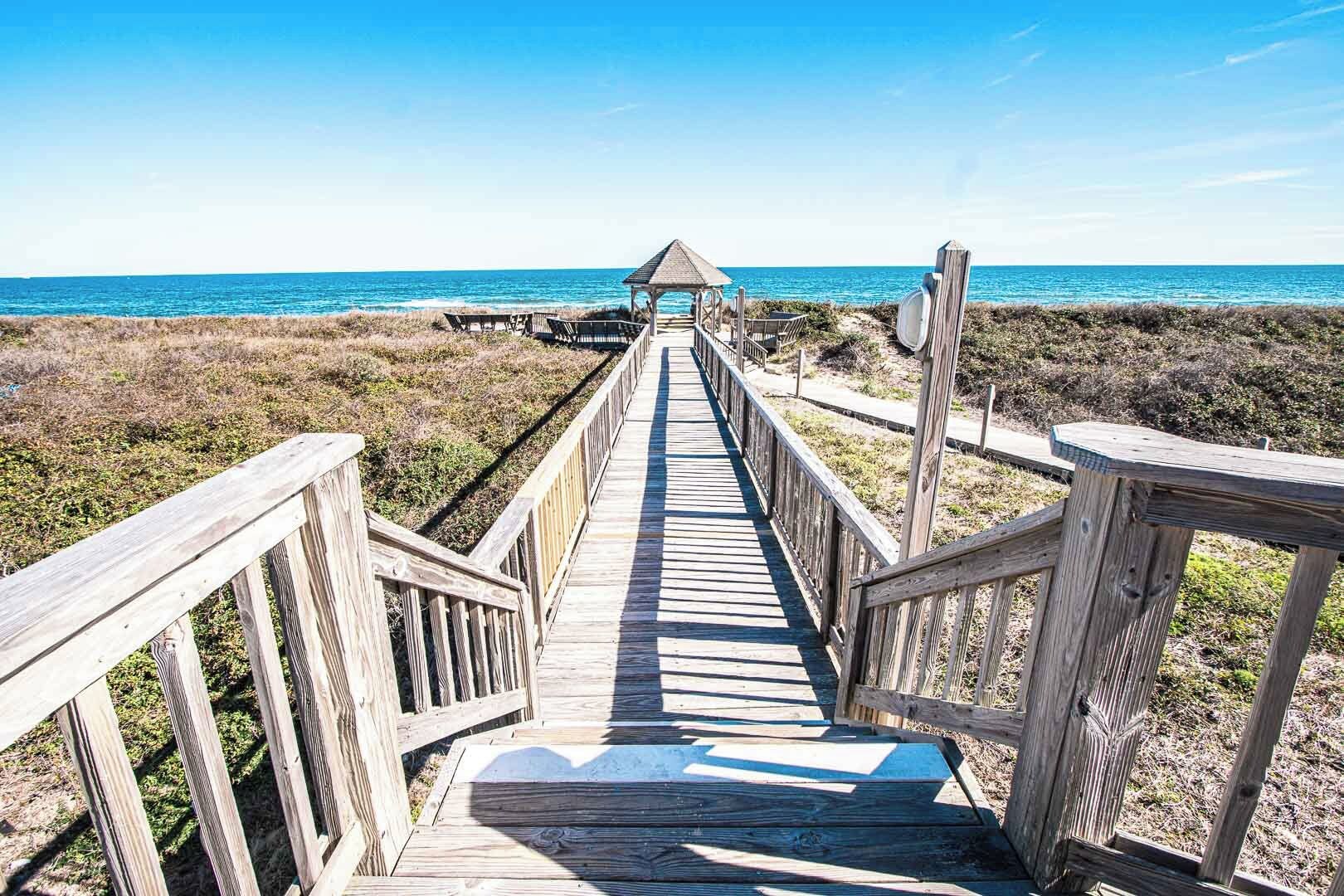 A wooden boardwalk leading to a beach with a gazebo at the end.