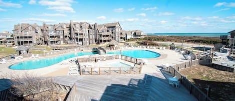 A resort with a large pool area, multiple decks, and a view of the beach.