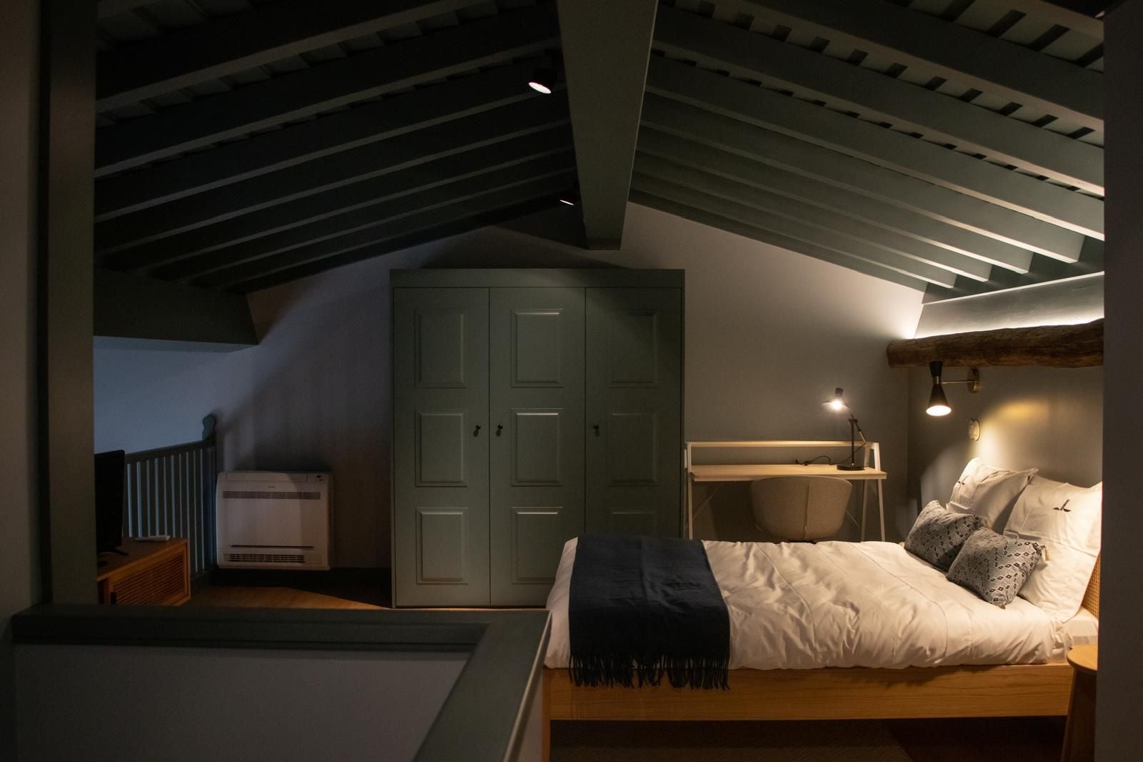 A bedroom with a bed, bedside table, lamp, and wardrobe.