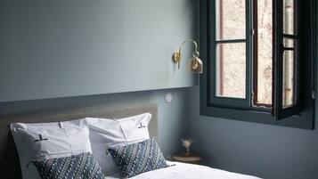 Quarto com cama, mesa de cabeceira, abajur e janela.
