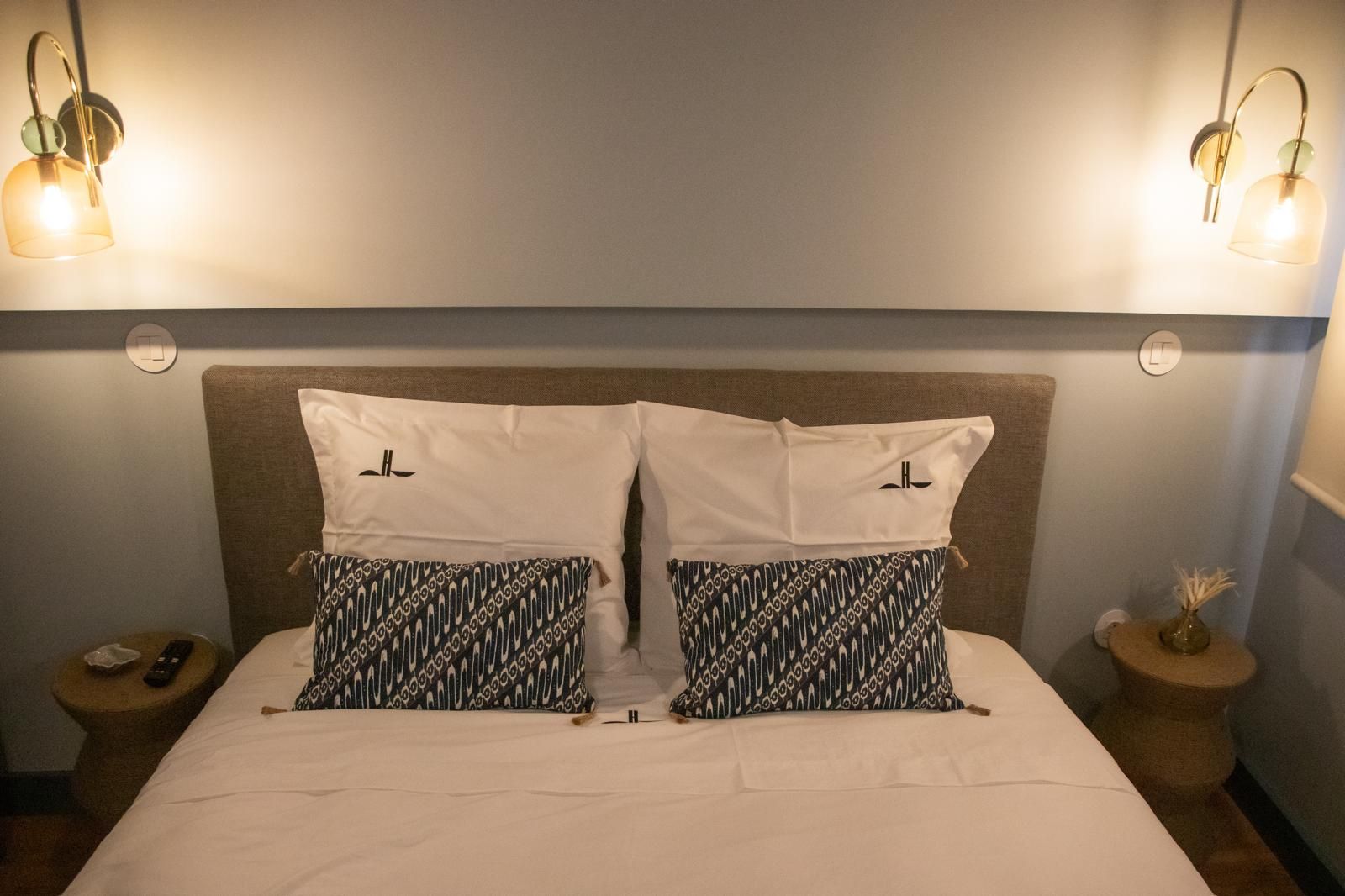 Een hotelkamer met een bed, twee nachtkastjes en twee wandlampen.