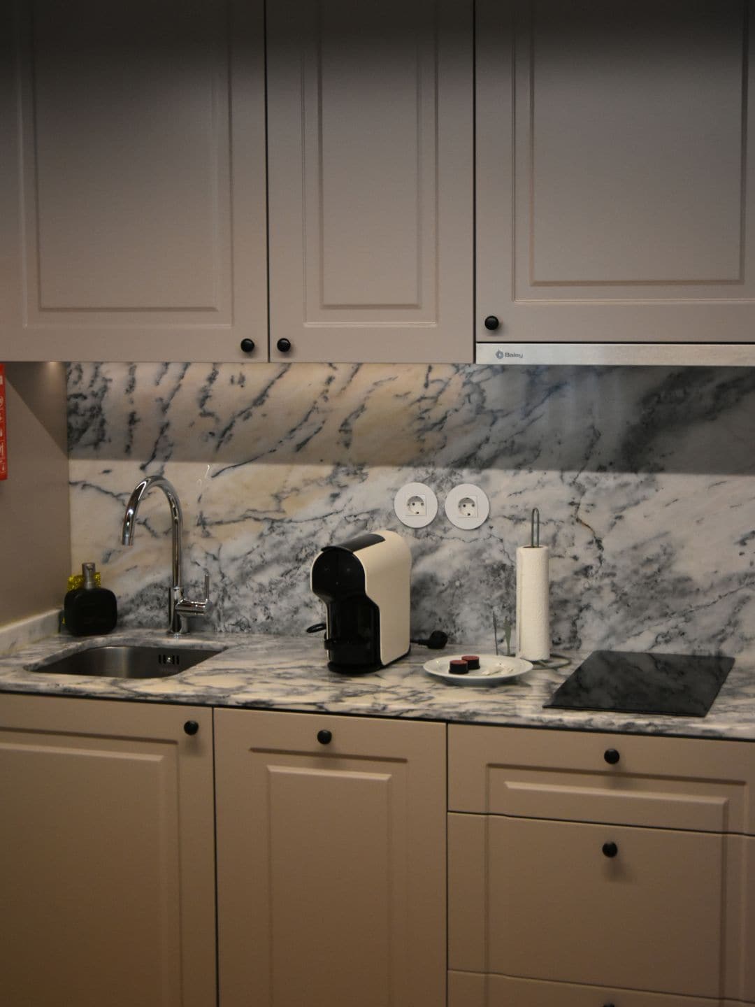 A kitchen with a marble countertop, a coffee machine, a toaster, and a sink.