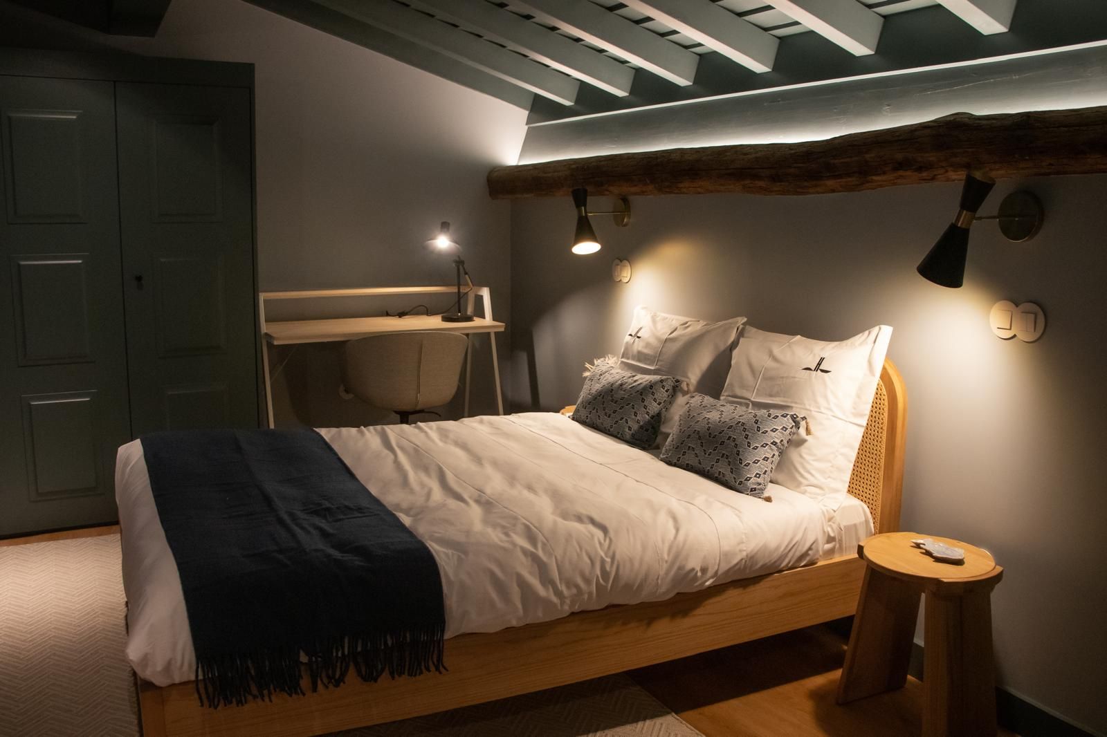 A bedroom with a bed, bedside table, desk, and chair.
