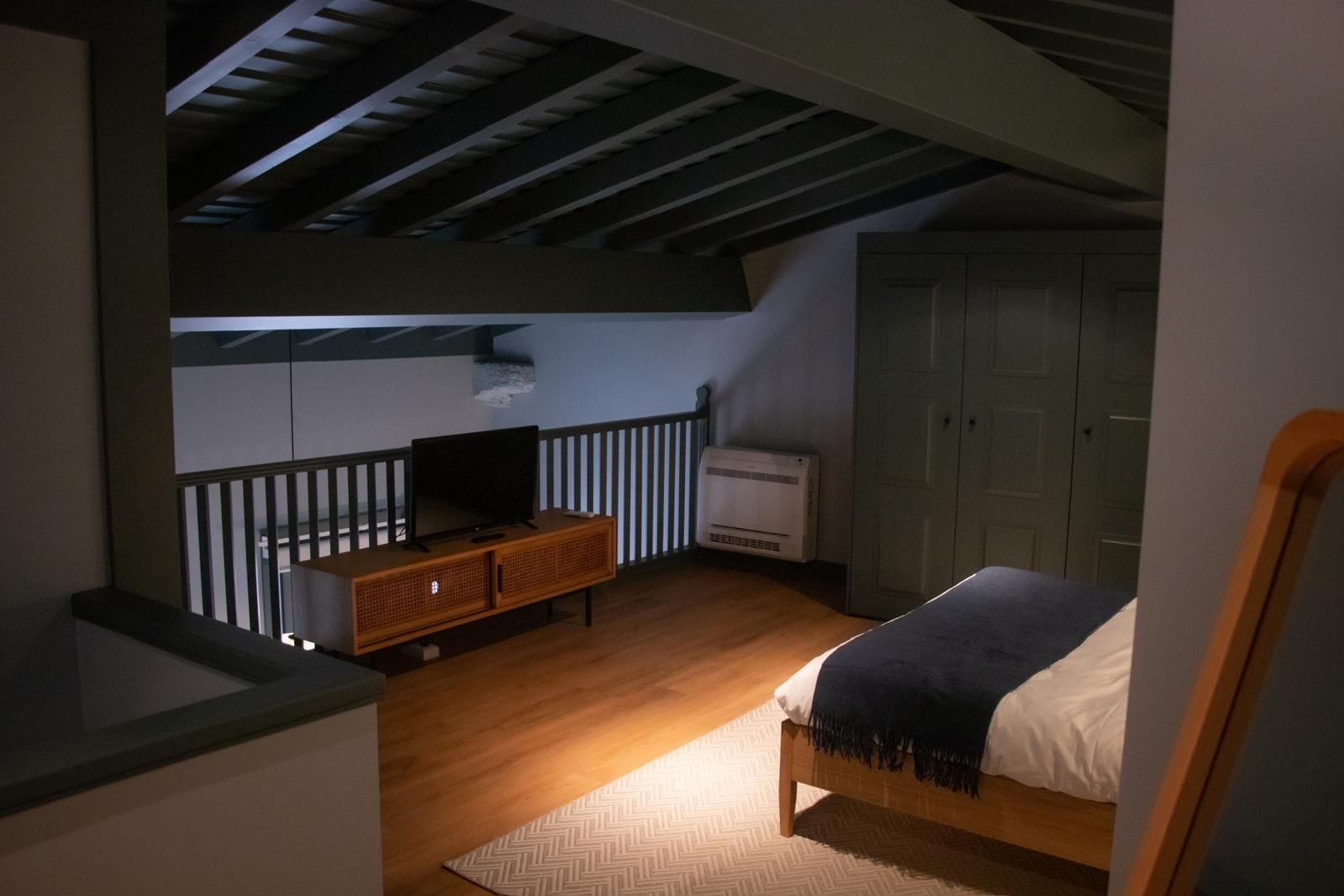 A bedroom with a bed, a TV, a wardrobe, and a radiator.