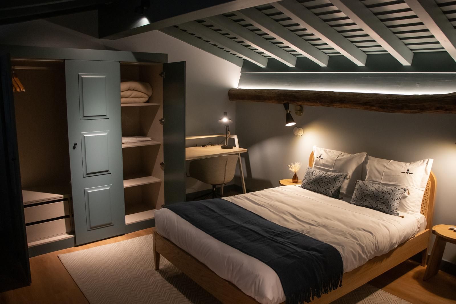 Un dormitorio con cama, escritorio y armario.