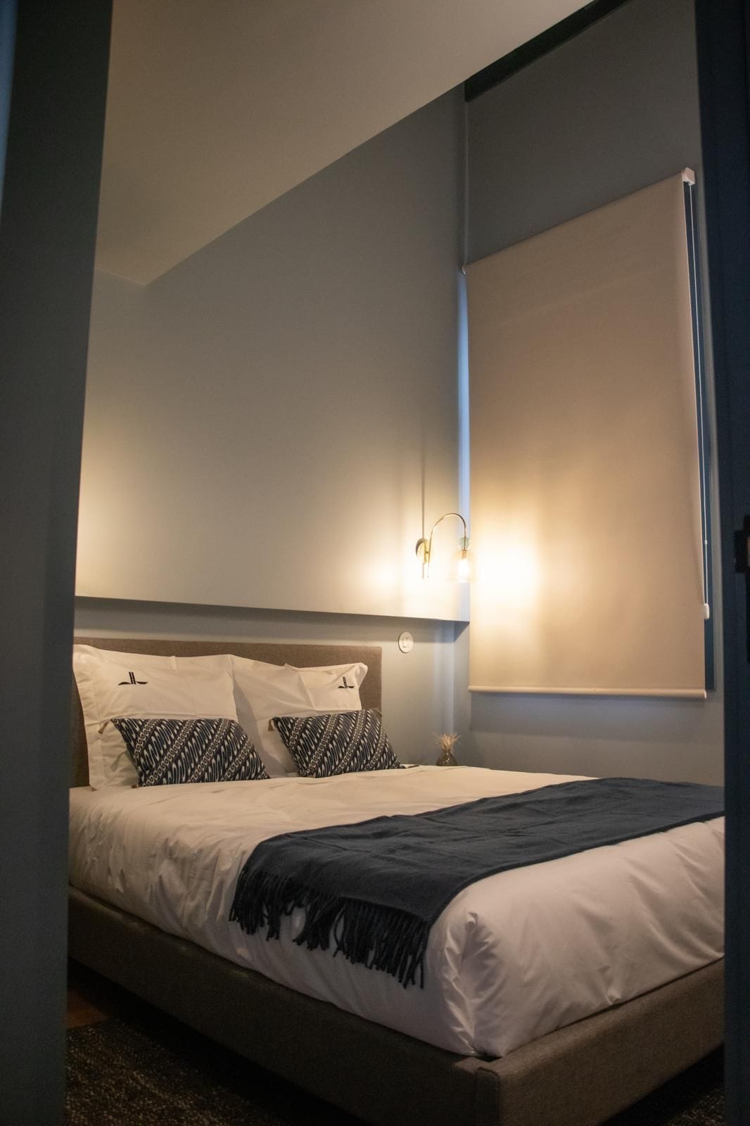 Ein Bett mit Kopfstuebe, Kissen und Decke.