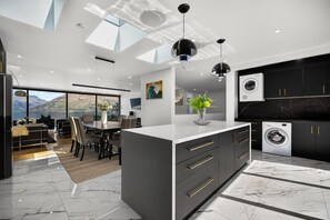 A modern kitchen with a central island, built-in appliances, and a view of the outdoors. - Luxury Away - The Outlook-Free Parking-BBQ (Queenstown)