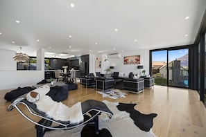 A modern living room with a sofa, a coffee table, and a dining area. - Luxury Away - The Outlook-Free Parking-BBQ (Queenstown)