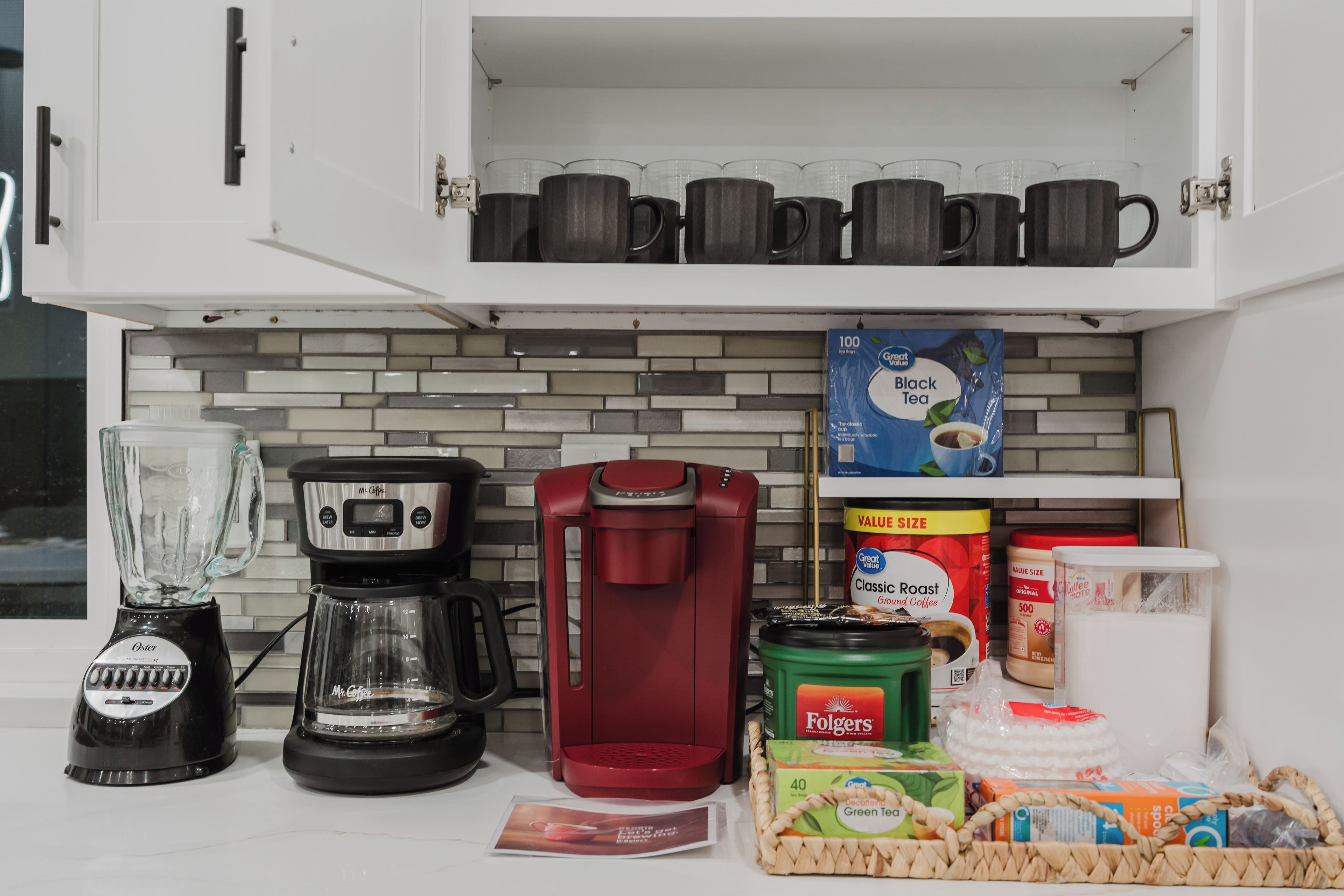 Una cocina con cafetera, licuadora y armarios para guardar utensilios.