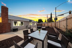 An outdoor patio with a table and chairs, a barbecue grill, and a brick wall. - Hot Tub, King Bed, Garage, Gated Yard, Ranch-Style (Spring Valley)