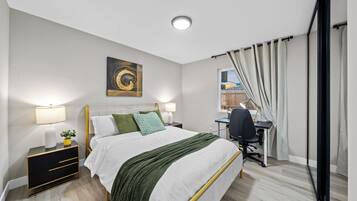 A bedroom with a bed, bedside tables, a desk, and a window with curtains.