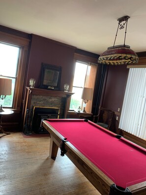 A room with a pool table, a fireplace, and a chandelier.