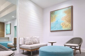 A modern interior with a sofa, ottoman, and chairs, a wall-mounted painting, and a textured wall. - ~NEW~ Modern Oceanfront at Waikiki Beach Tower (Honolulu)