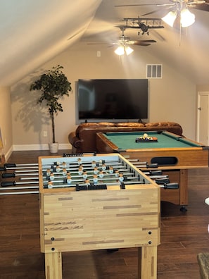 A cozy room with a foosball table, a pool table, a television, and a ceiling fan. - Casa 746 Fort Worth Downtown Stockyards Retreat (Fort Worth)