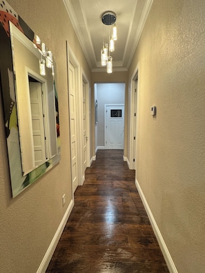 A hallway with wooden flooring, white doors, and pendant lighting. - Casa 746 Fort Worth Downtown Stockyards Retreat (Fort Worth)