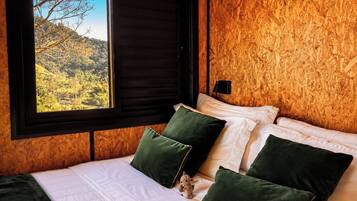 A room with a bed, a window, and a view of a landscape.