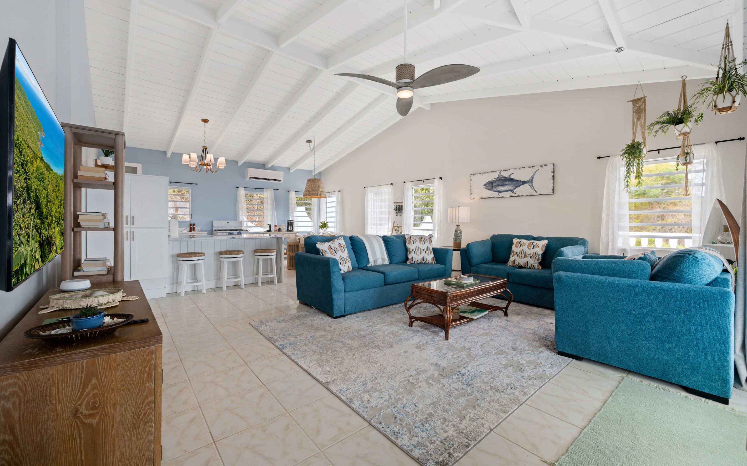 A spacious living area with a large blue sofa, a coffee table, and a kitchen in the background.
