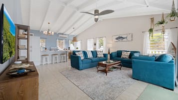Ein großzügiger Wohnbereich mit einem großen blauen Sofa, einem Couchtisch und einer Küche im Hintergrund.