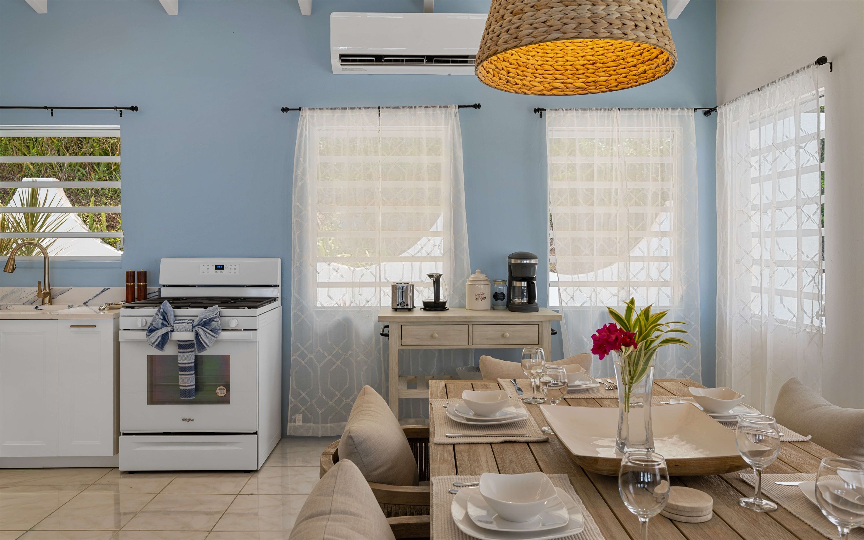 A kitchen with a stove, a coffee maker, and a dining area with a table set for two.