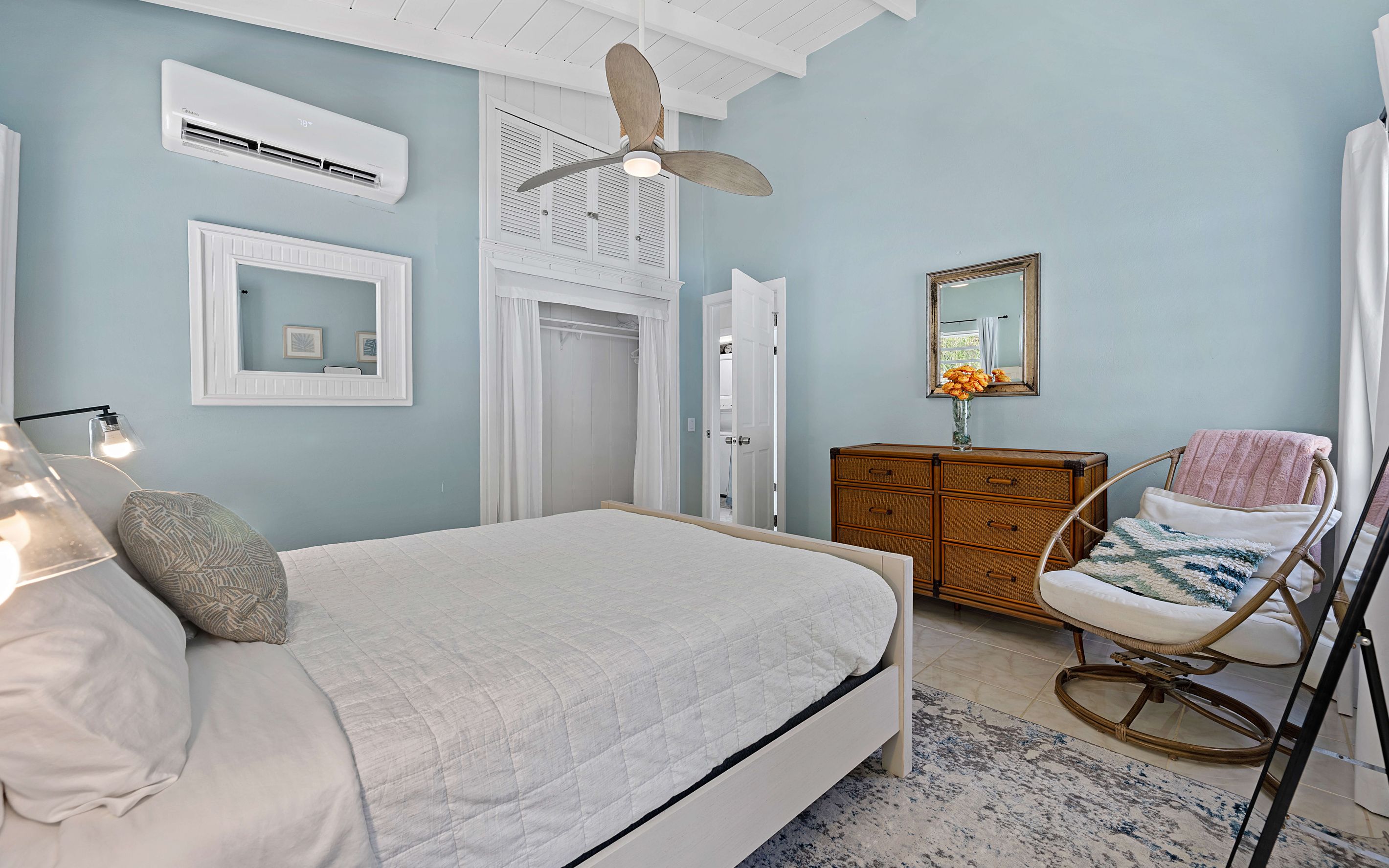 A bedroom with a bed, a dresser, a chair, and a ceiling fan.