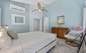 A bedroom with a bed, a dresser, a chair, and a ceiling fan.