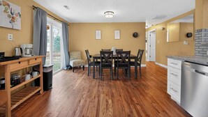 Una cucina compatta con zona pranzo, pavimento in legno e vista dalla finestra.